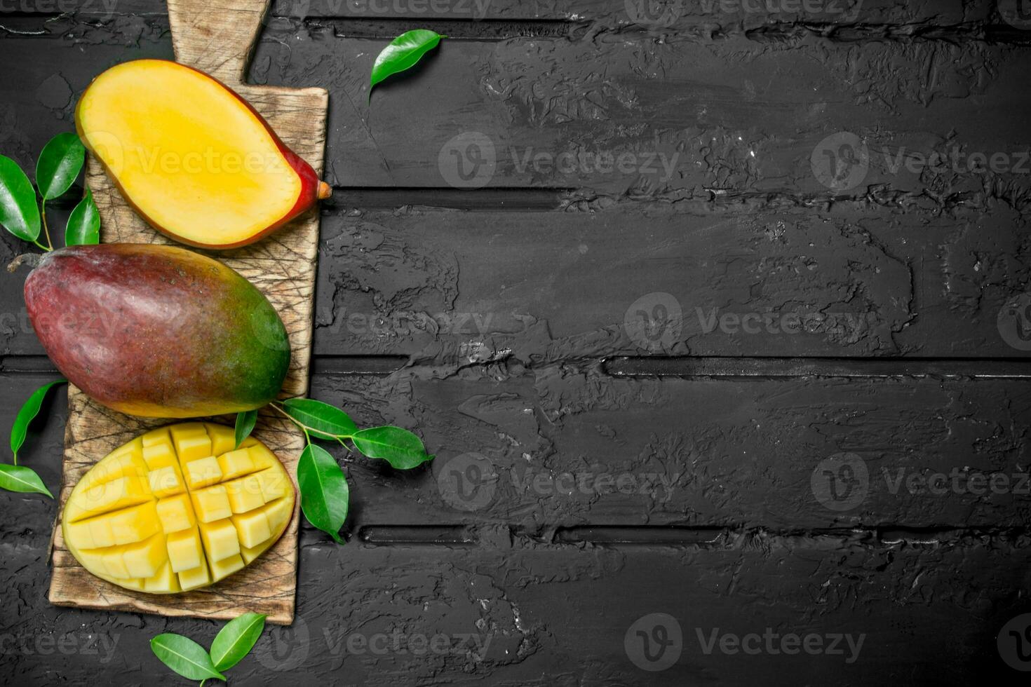 Whole and pieces of mango on the cutting Board. photo