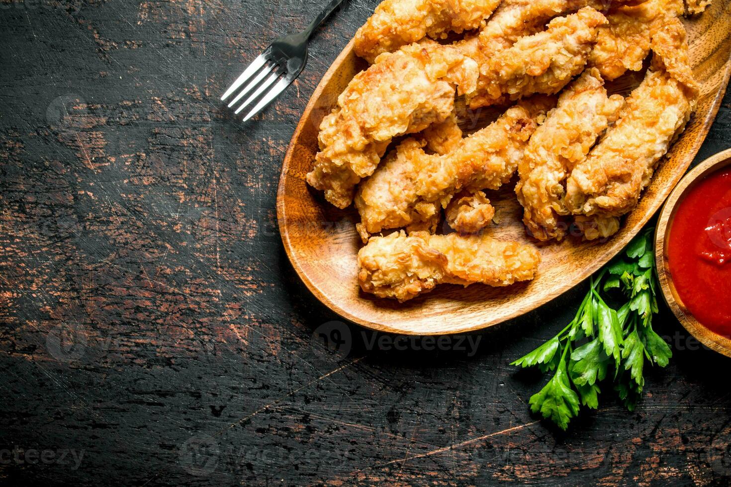 Chicken strips on a plate with greens and sauce. photo