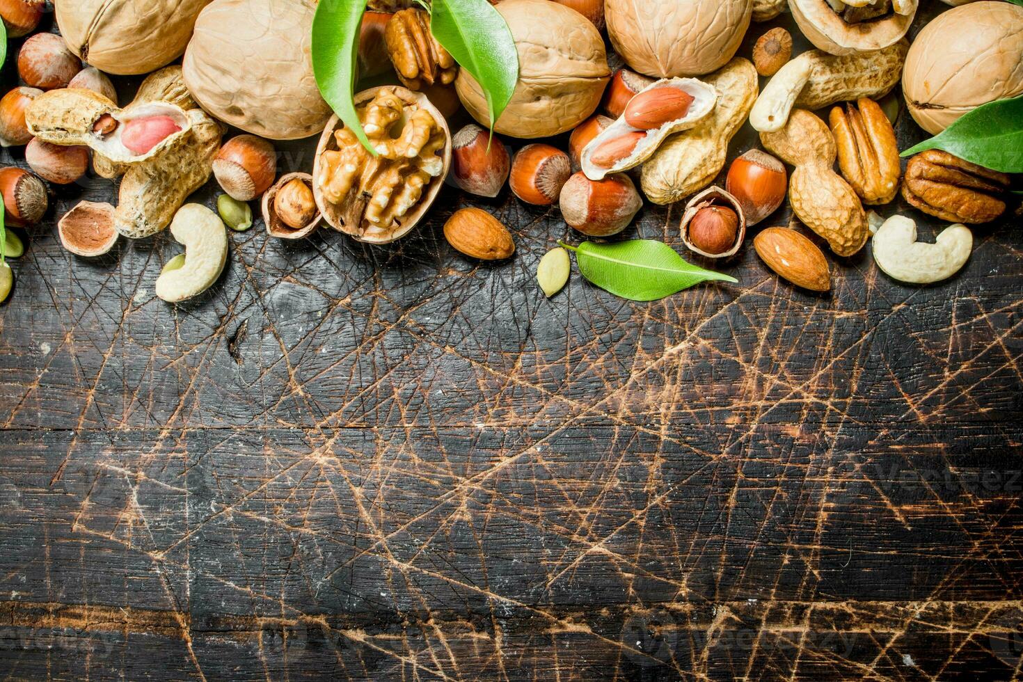 Nuts background. Different kind of nuts with green leaves. photo
