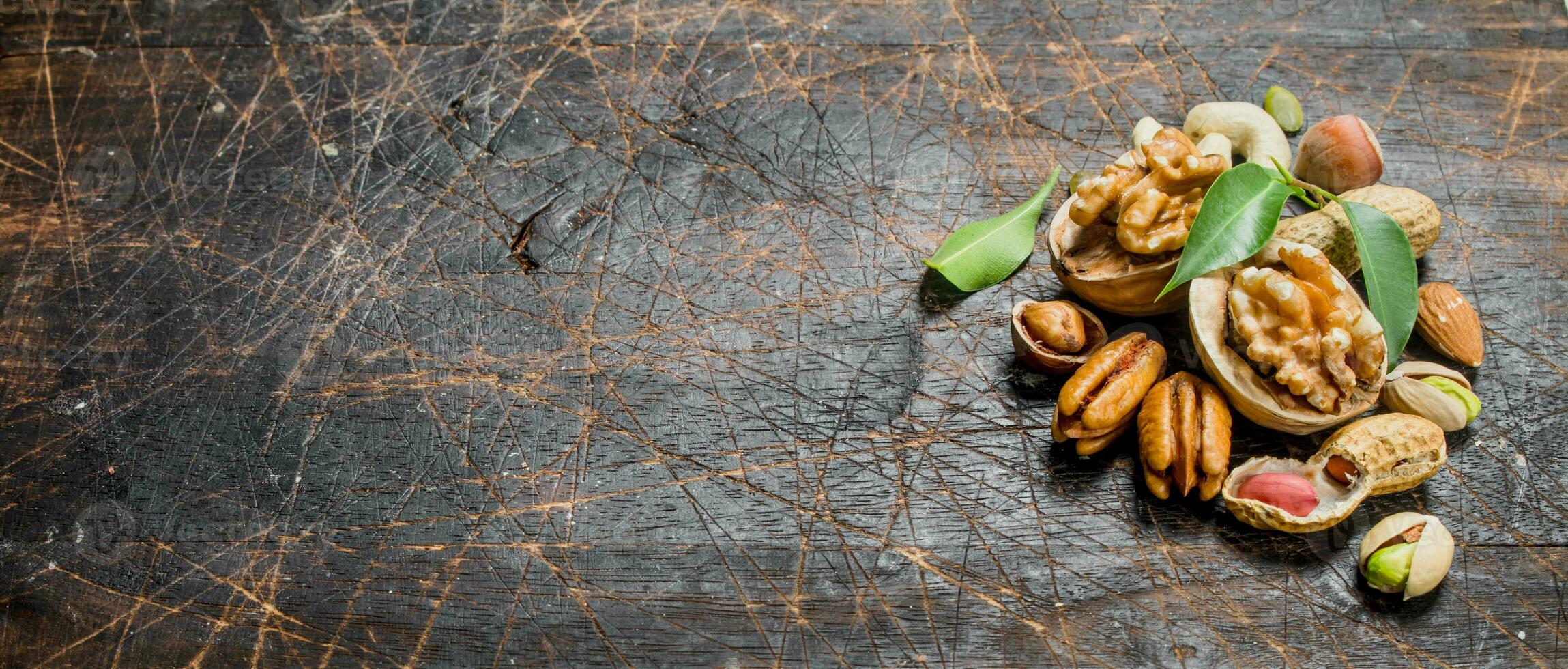 Nuts background. Assortment of different nuts with green leaves . photo