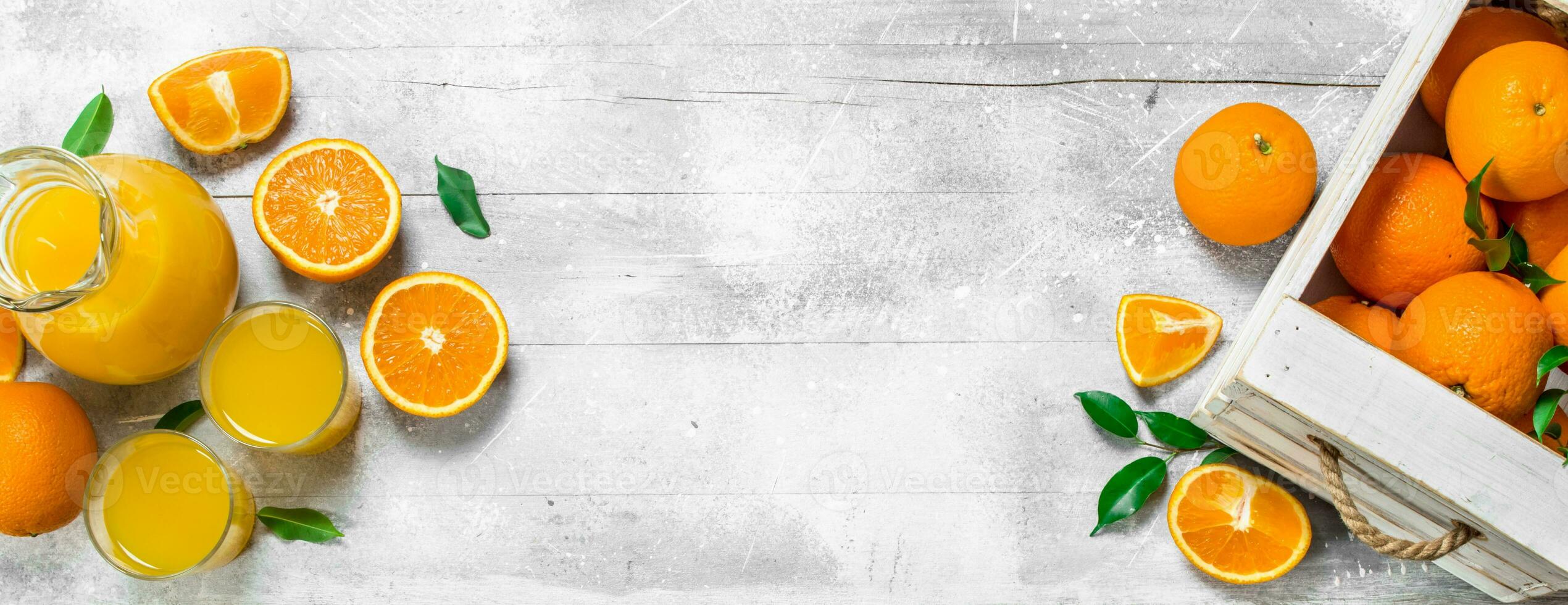 Orange juice in glass pitcher and fresh oranges. photo