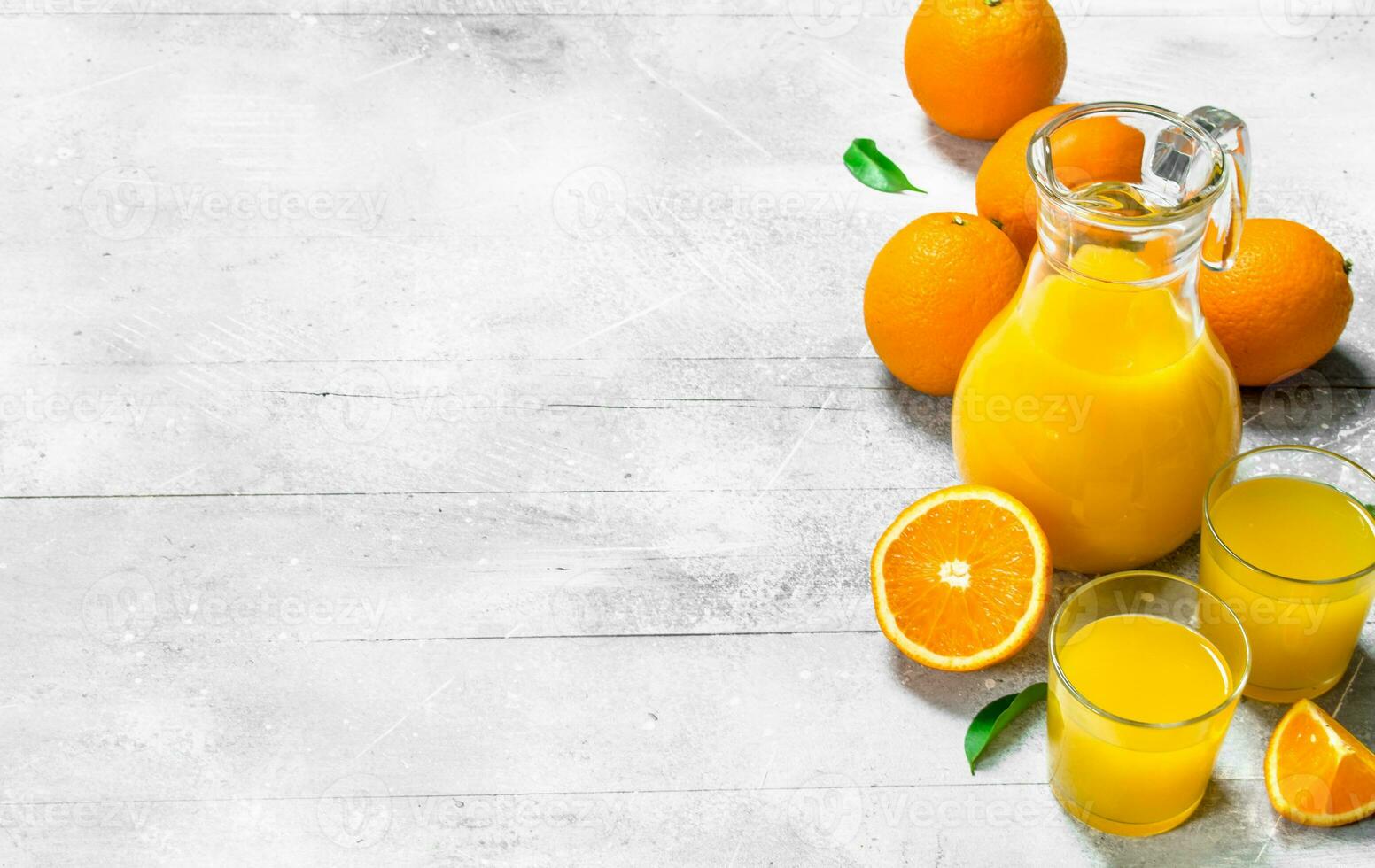 Orange juice in glass pitcher and fresh oranges. photo