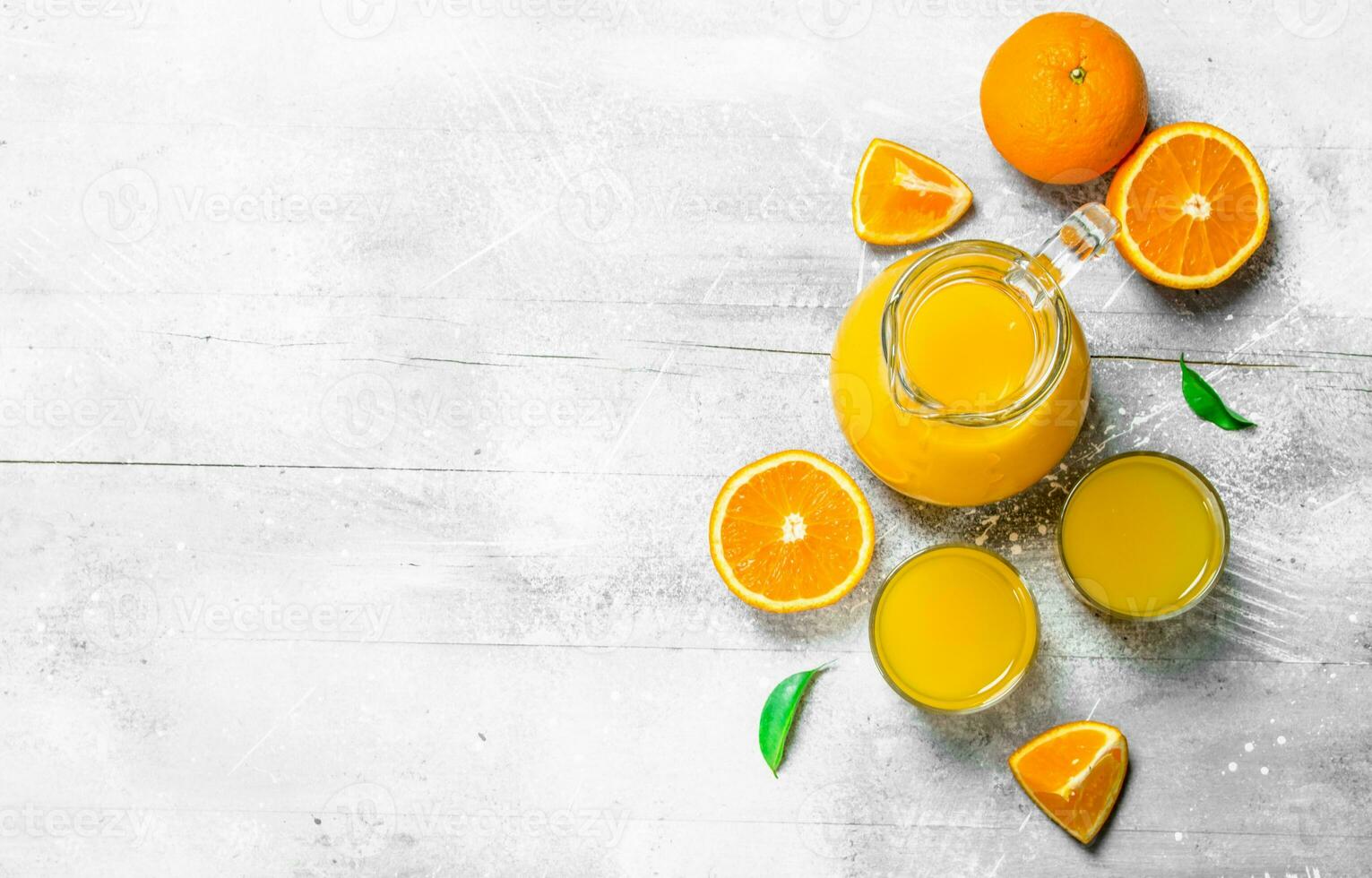 Orange juice in the pitcher and slices of fresh oranges. photo