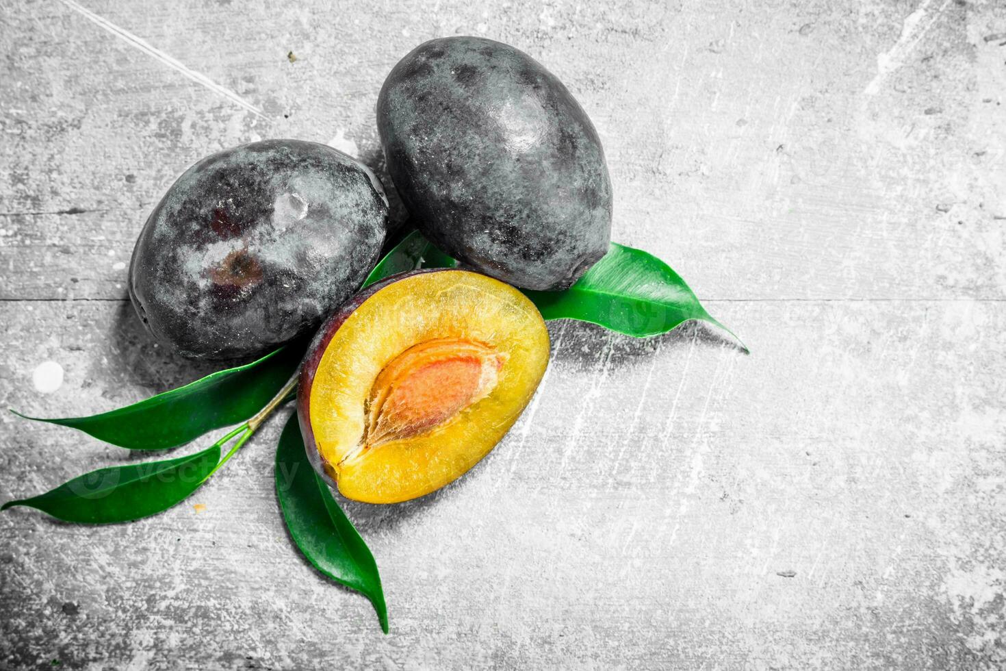 Half and whole plums with leaves. photo