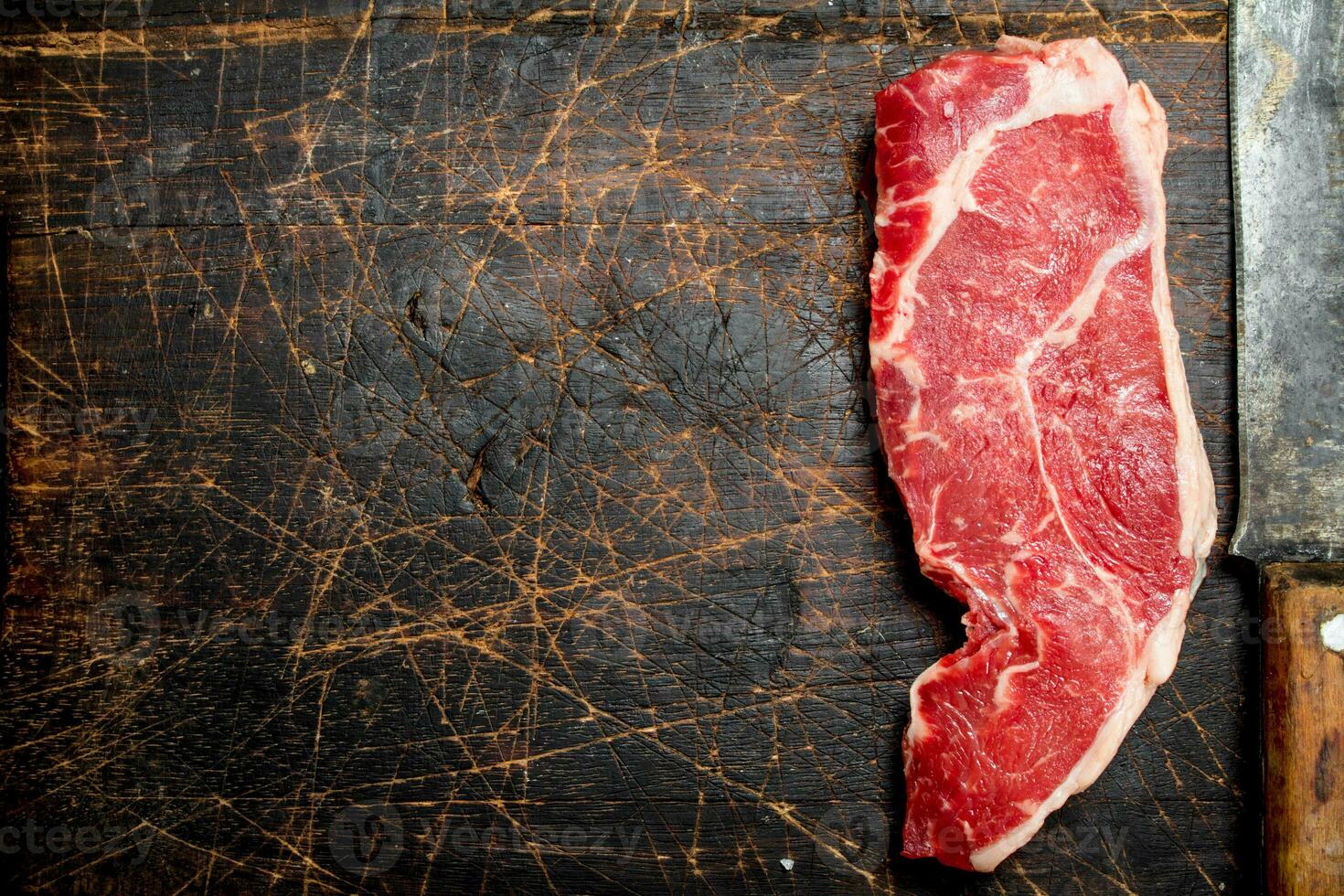 Raw beef steak with hatchet. photo