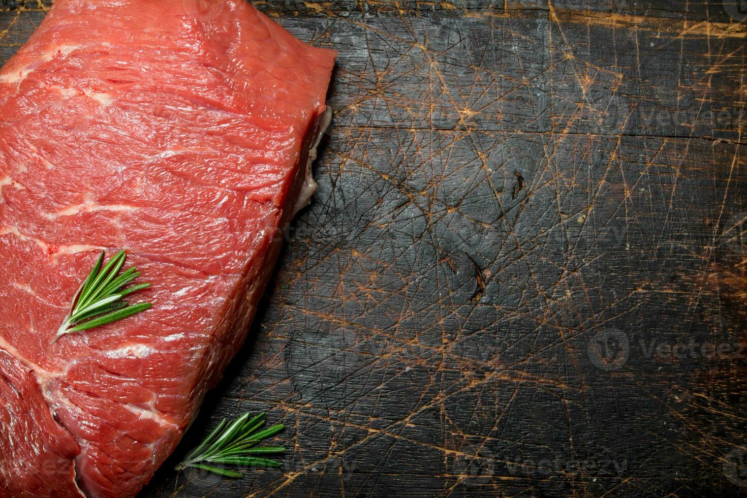 Raw meat. A piece of beef with rosemary. photo
