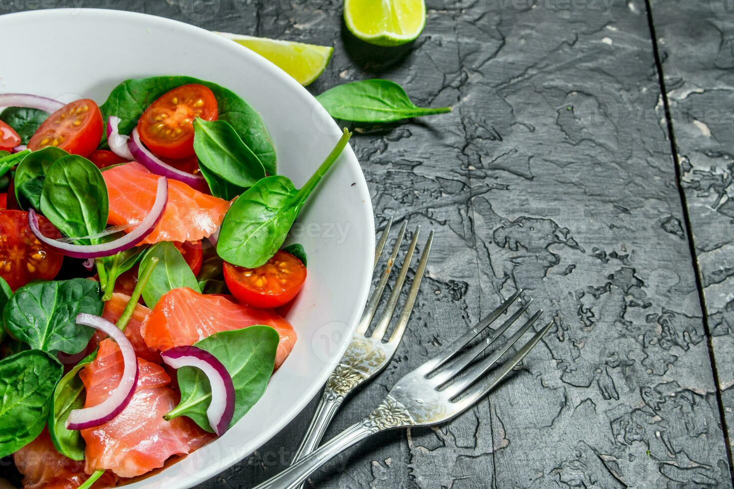 Fish salad. Salad with slices of salmon, tomatoes and spinach with lime juice. photo