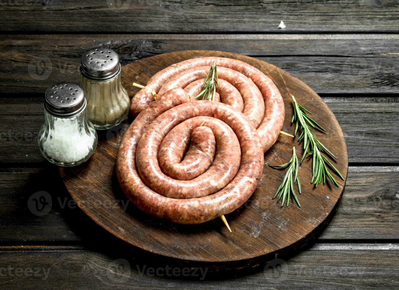 Raw sausages with herbs on a wooden Board. photo