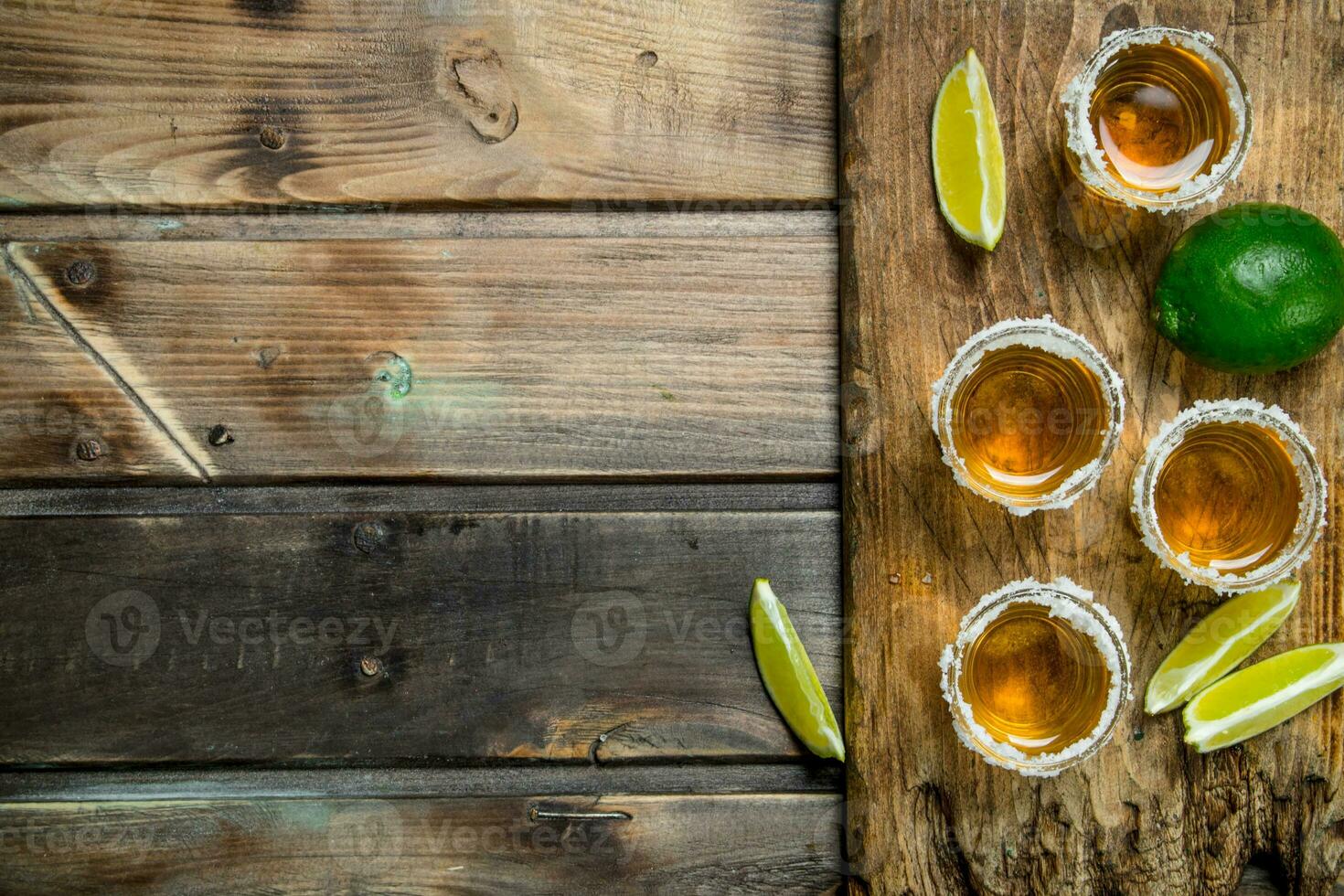 Tequila in a shot glass on a cutting Board with slices of lime. photo