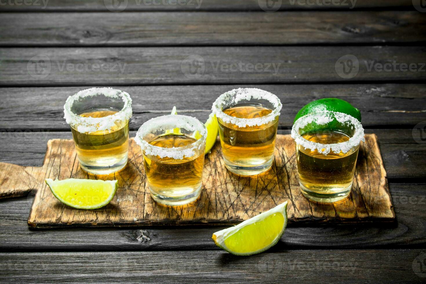 Tequila in a shot glass on a cutting Board with slices of lime. photo