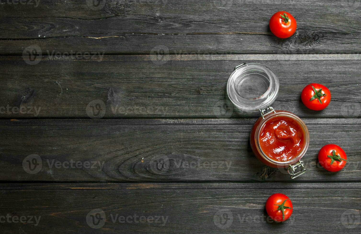 Tomato sauce in a glass jar and fresh tomatoes. photo