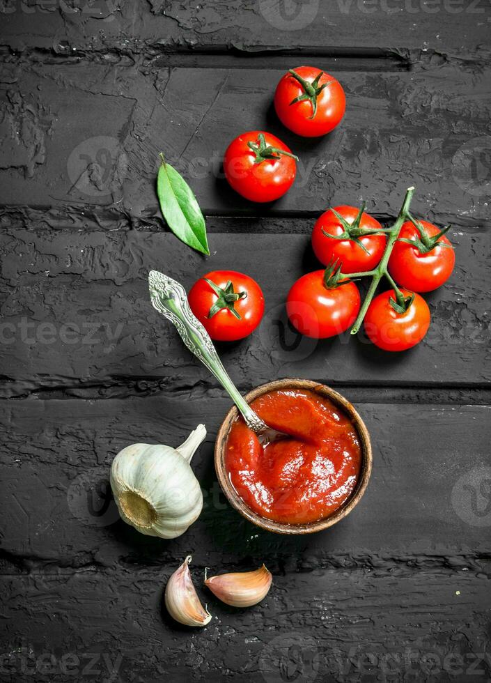 Tomato sauce in bowl with spoon and fresh garlic. photo