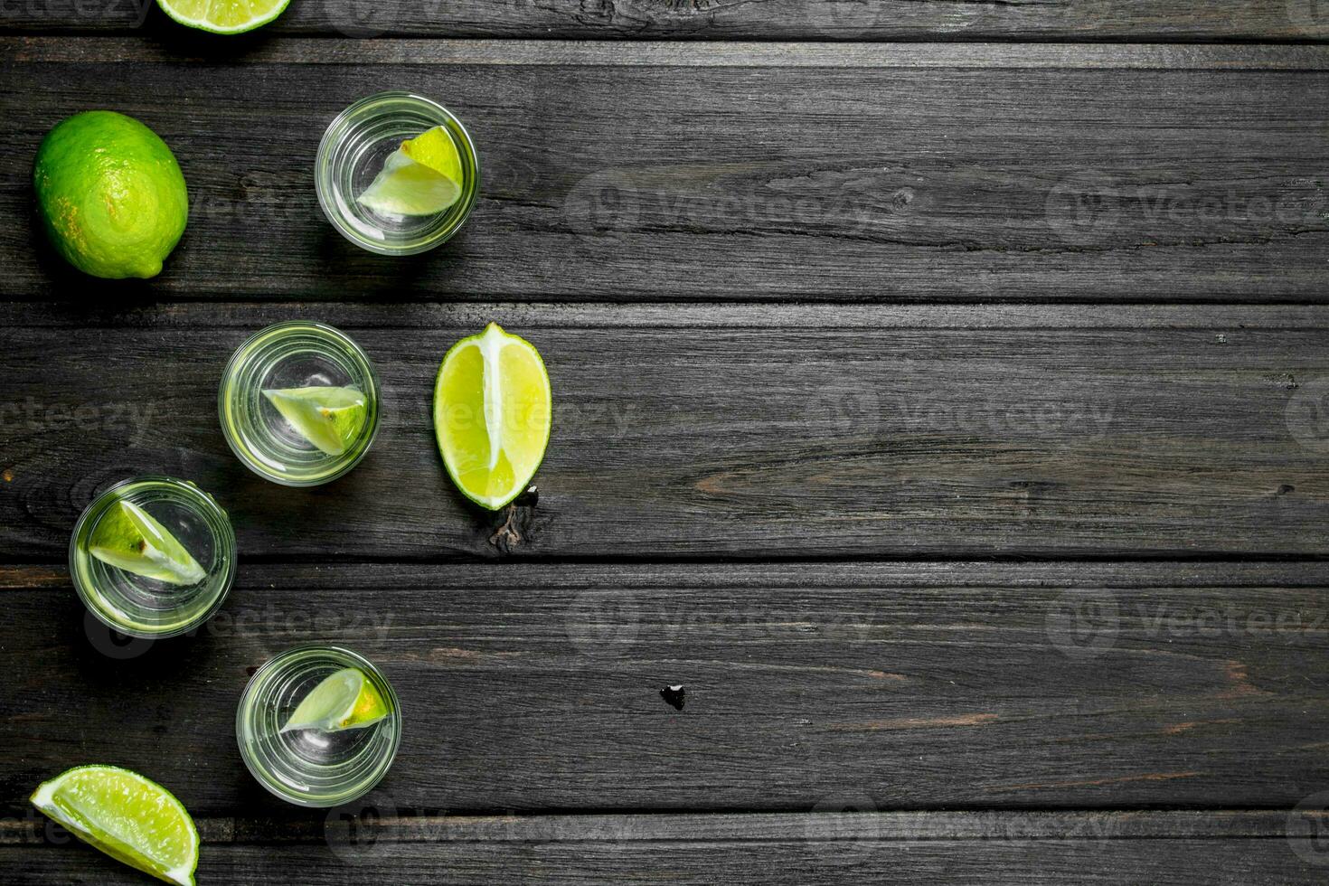 Vodka in a shot glass and lime slices. photo