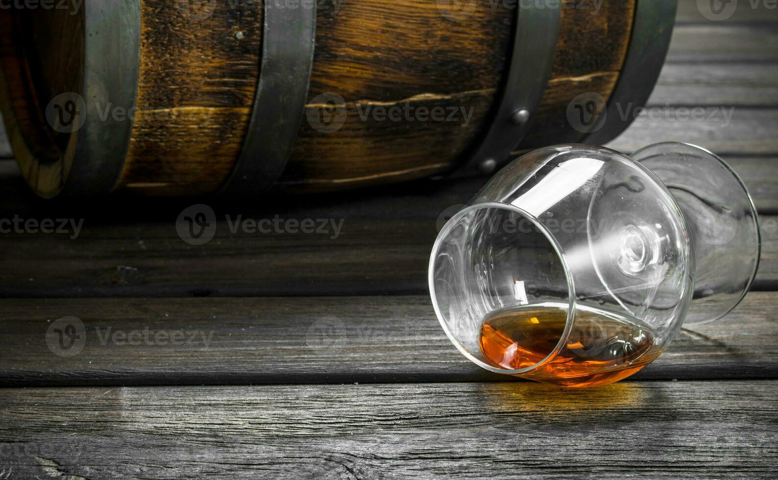 Cognac in a glass and a barrel. photo