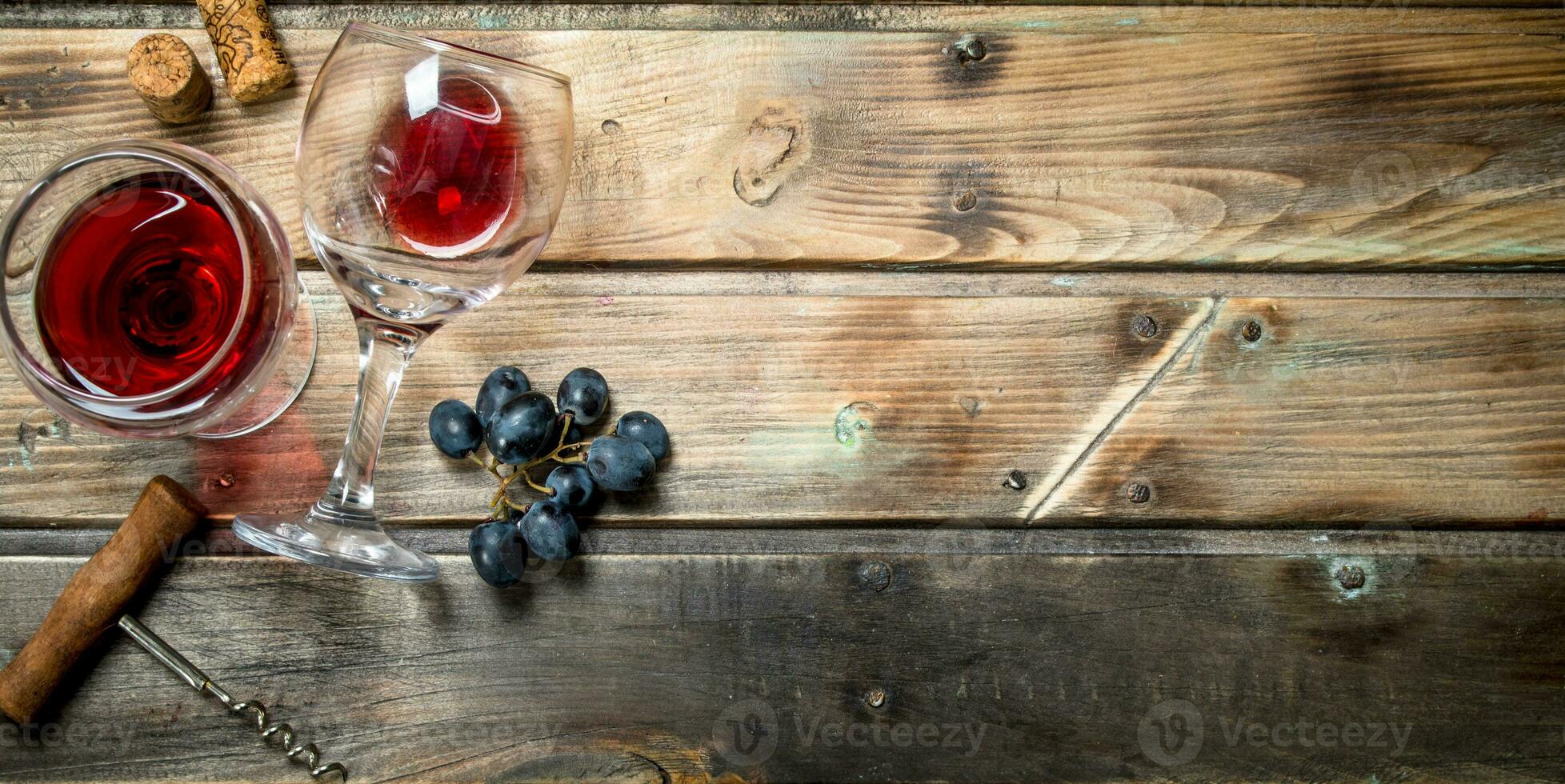 Red wine in a glass with grapes and a corkscrew. photo