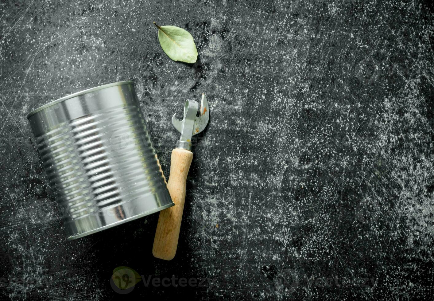 Closed tin can with a opener and a Bay leaf. photo