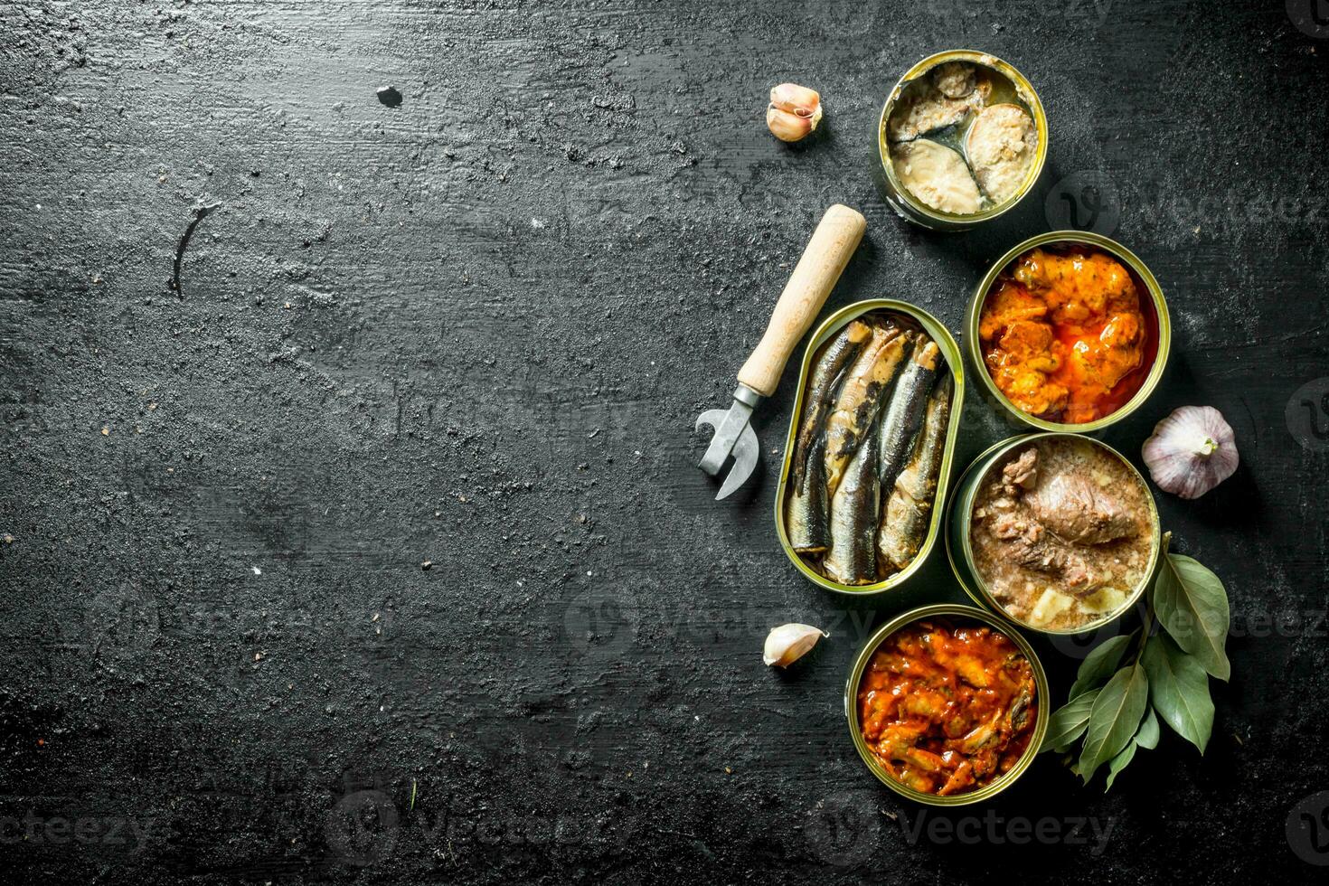 Canned food in various open cans with garlic cloves and Bay leaf. photo
