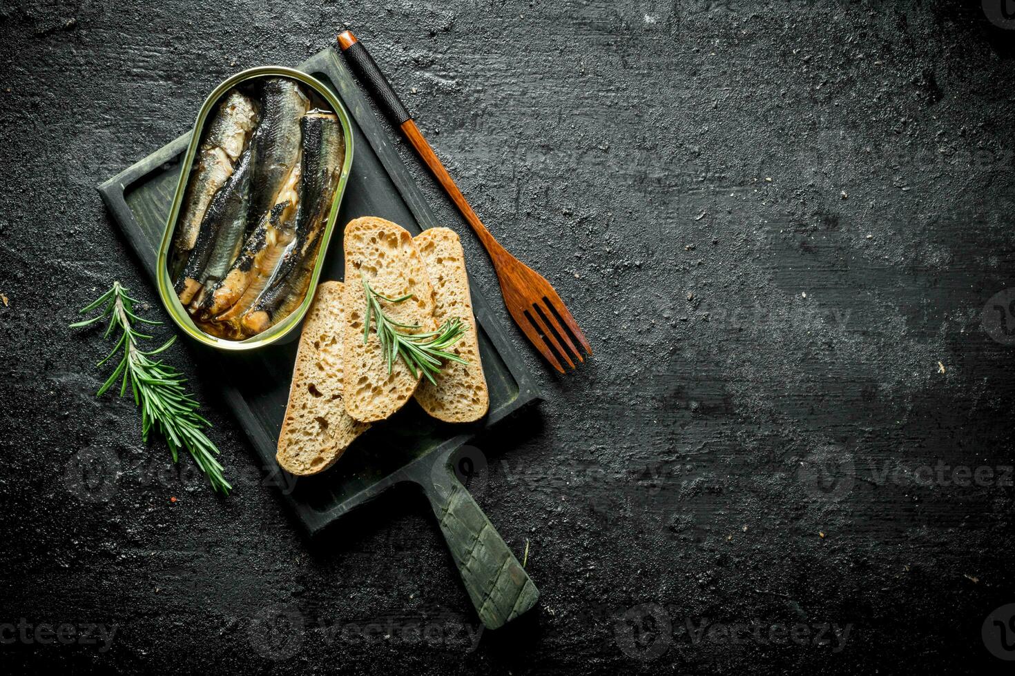 Sprats in a tin on a cutting Board with slices of bread. photo