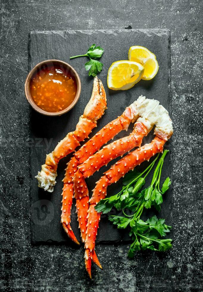Crab on a stone Board with sauce, parsley and lemon slices. photo