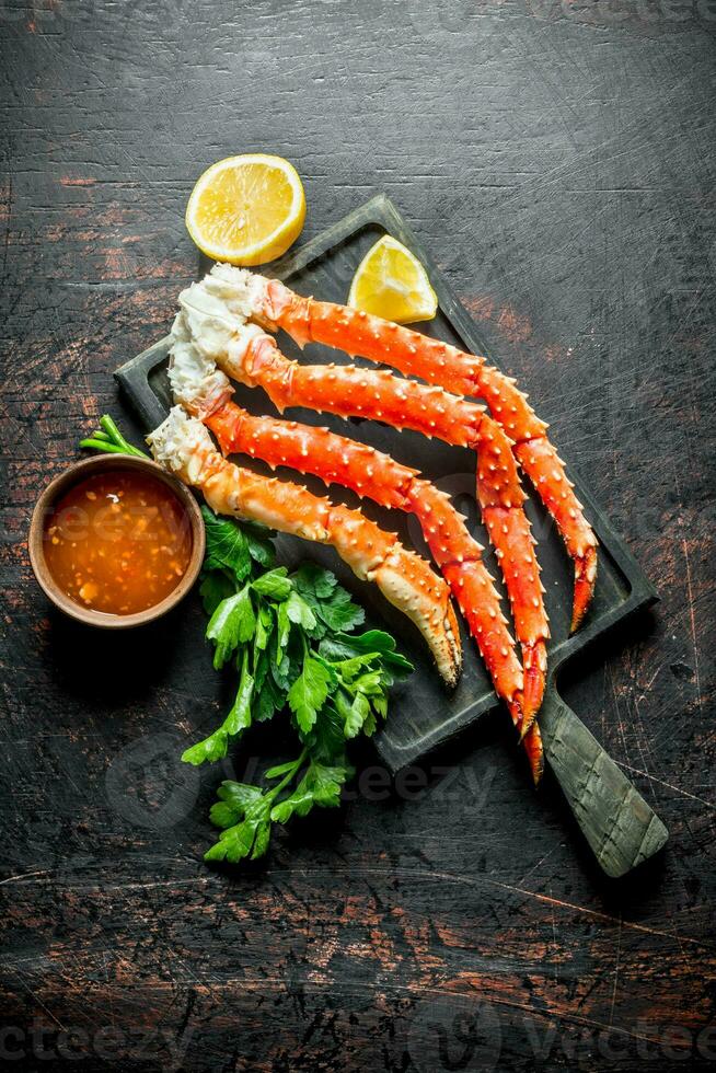 Crab on a chopping Board with parsley, sauce and lemon slices. photo