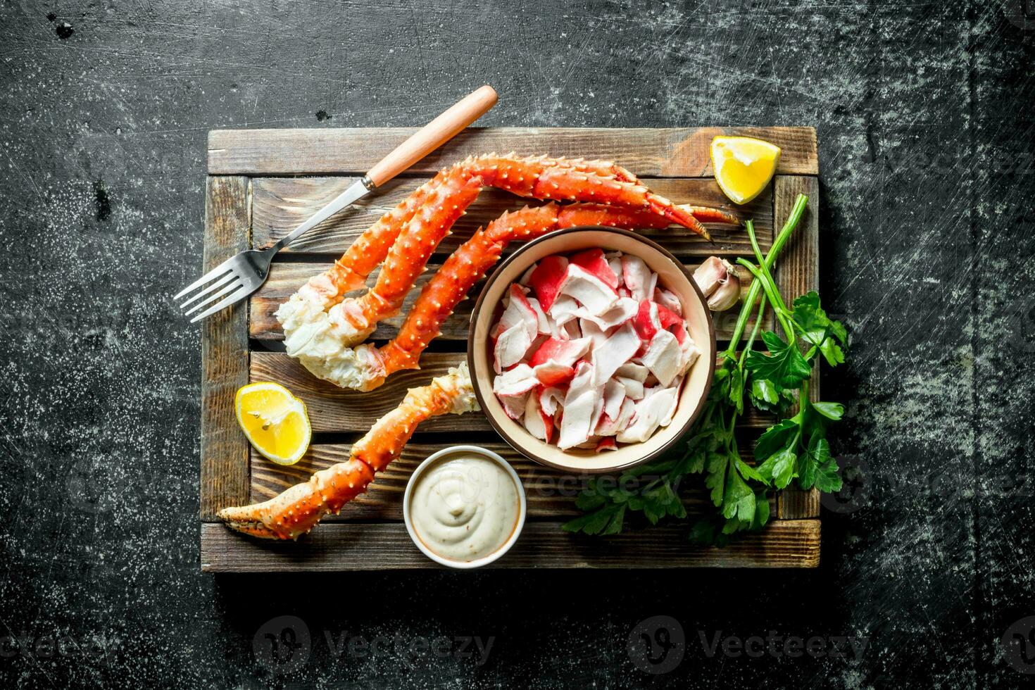 Crab meat and fresh crab on a wooden tray with lemon slices, sauce and herbs. photo