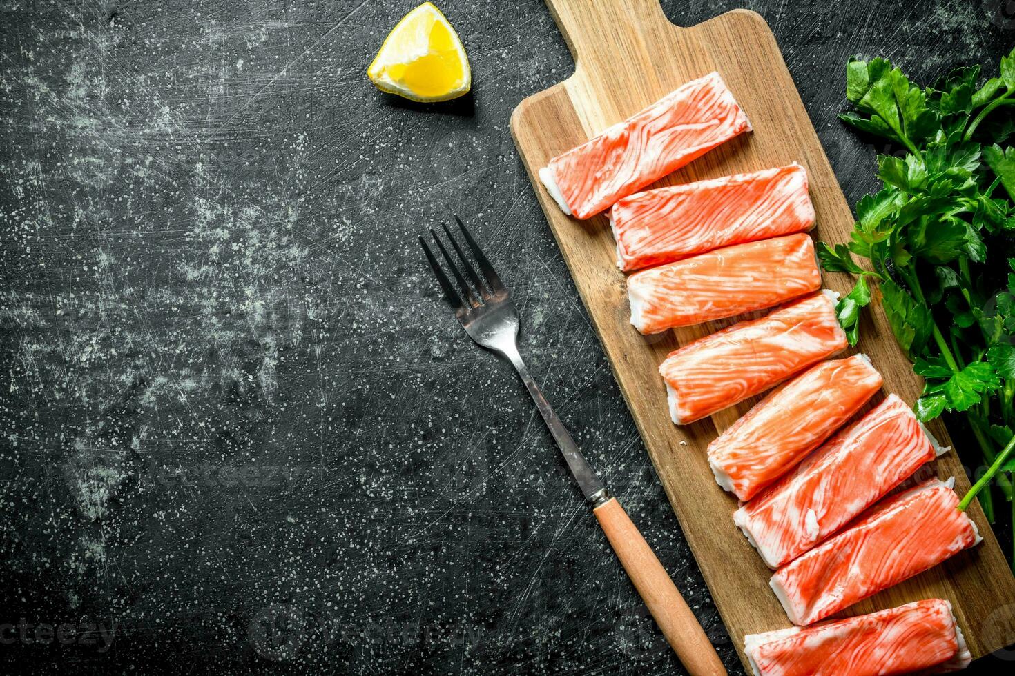 Crab sticks on a chopping Board with parsley and lemon. photo