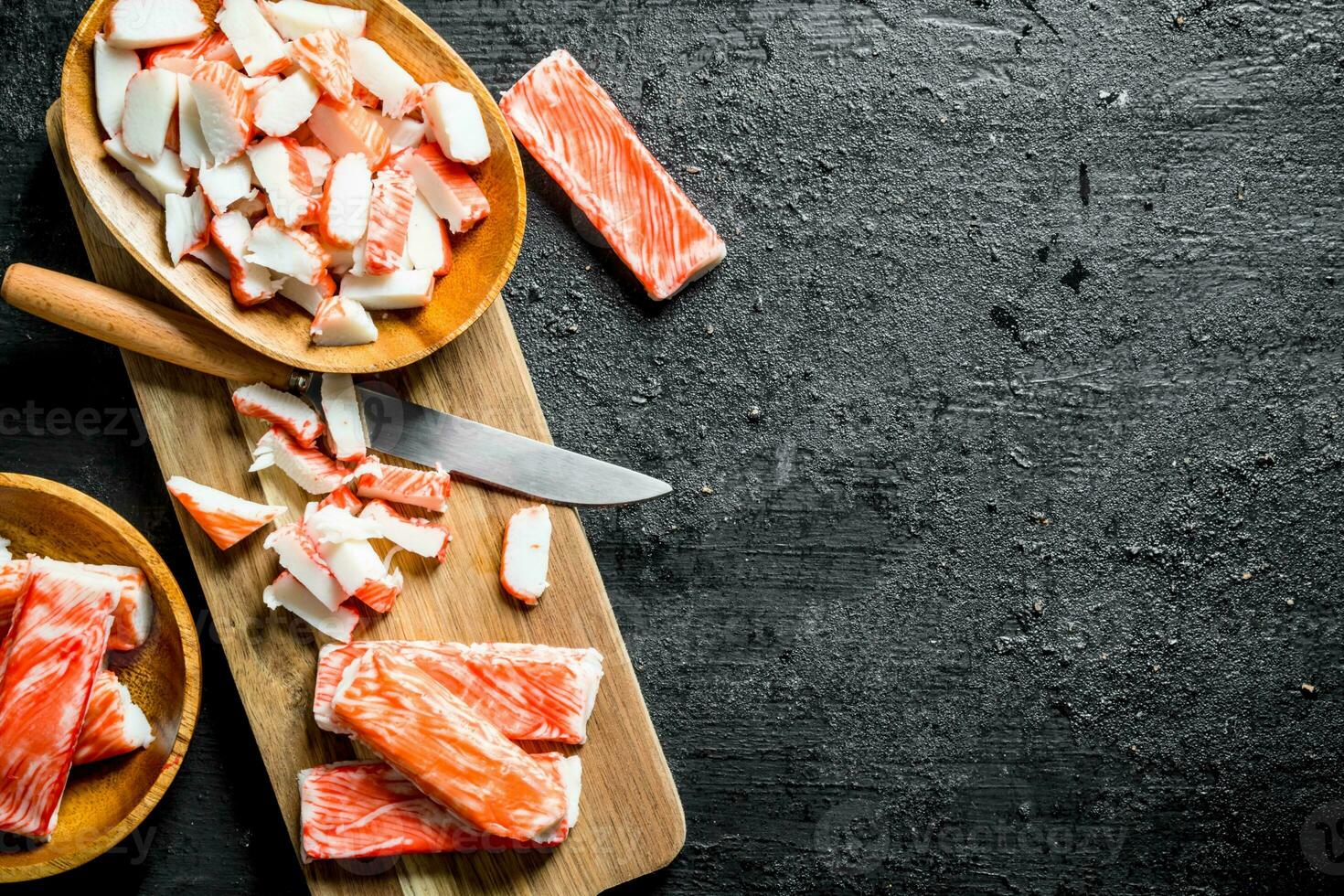 Pieces of crab sticks on a wooden cutting Board with a knife. photo