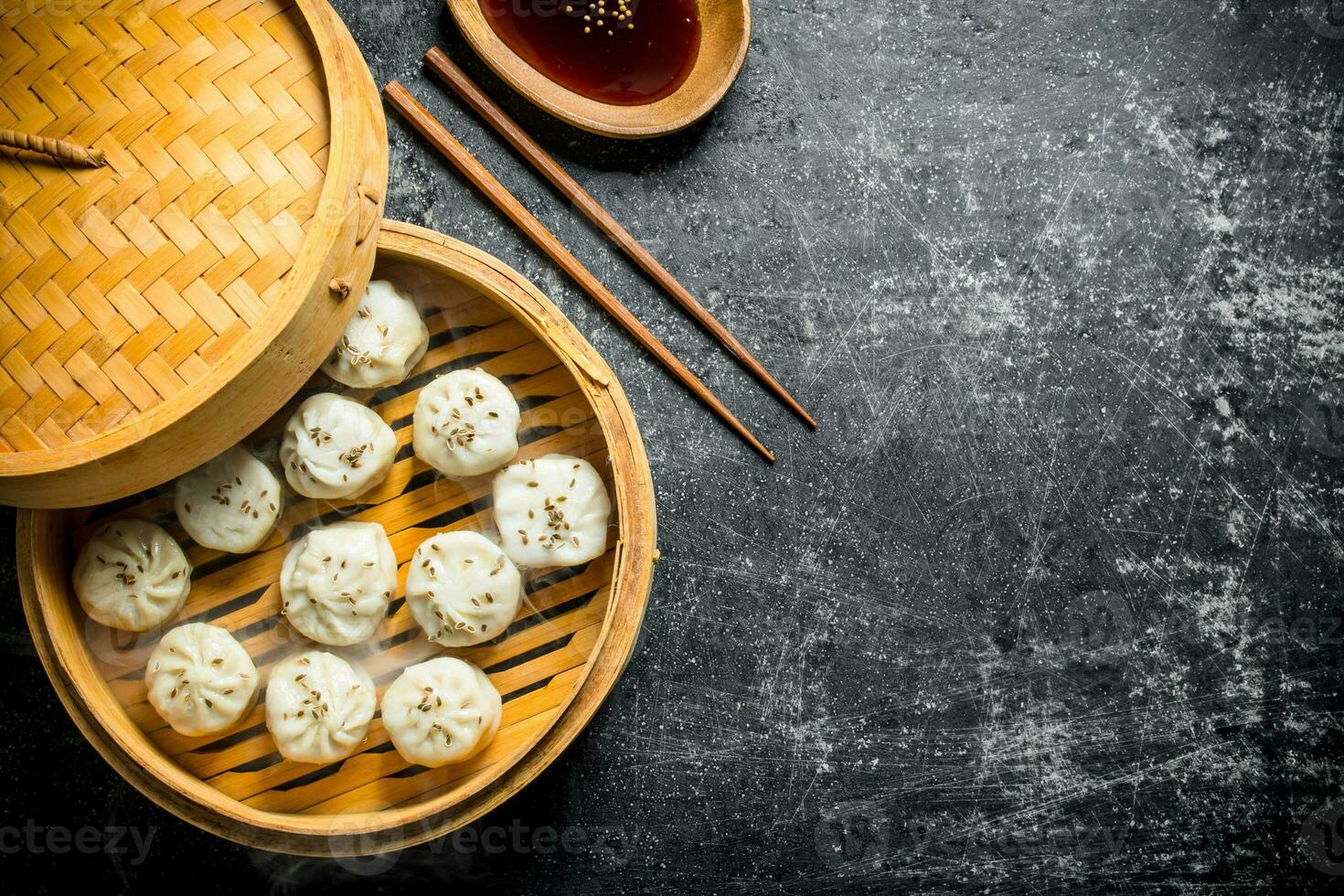 Fragrant manta dumplings in a bamboo steamer with soy sauce in a plate. photo
