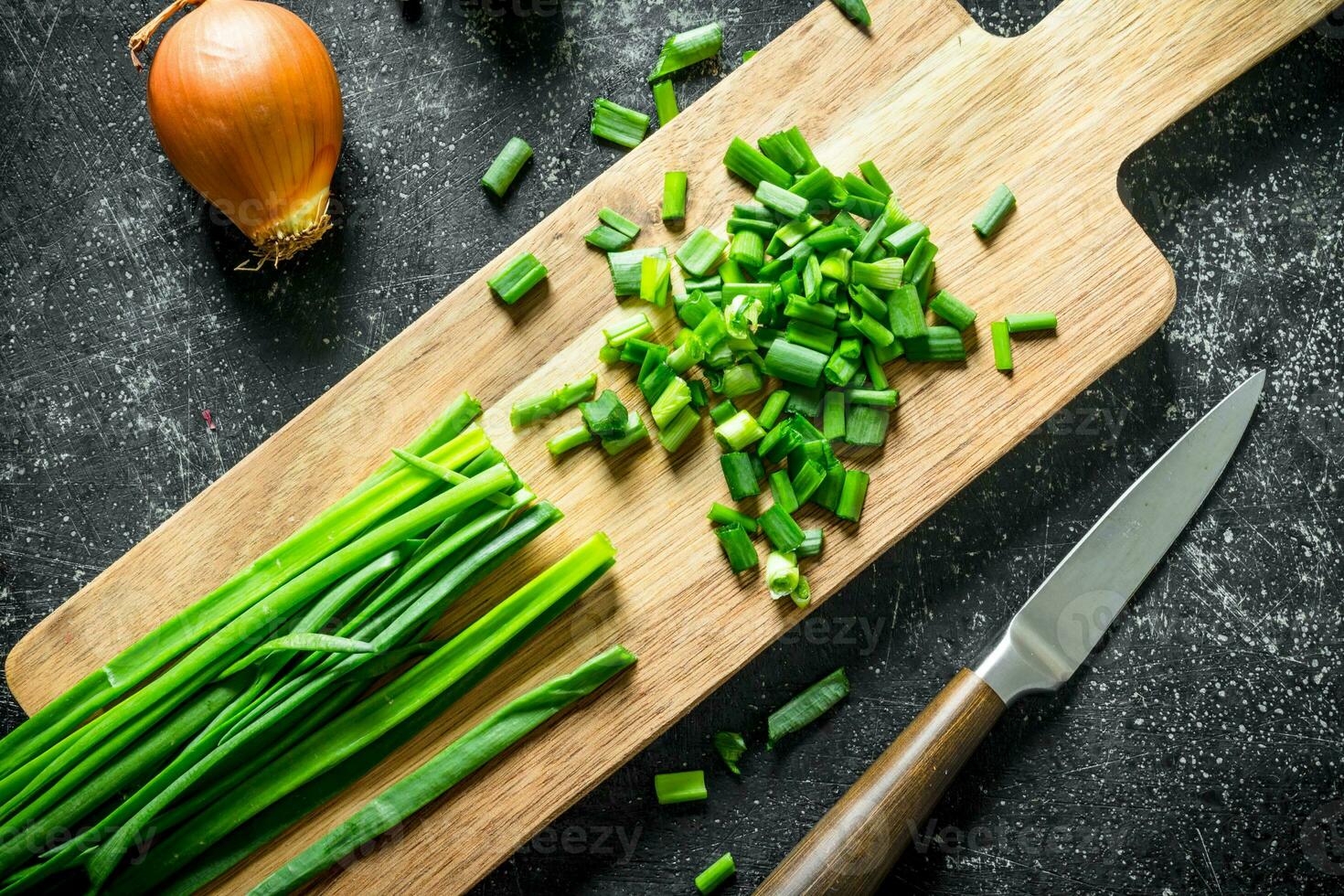 Chopped green onion on a cutting Board with a knife and onion. photo