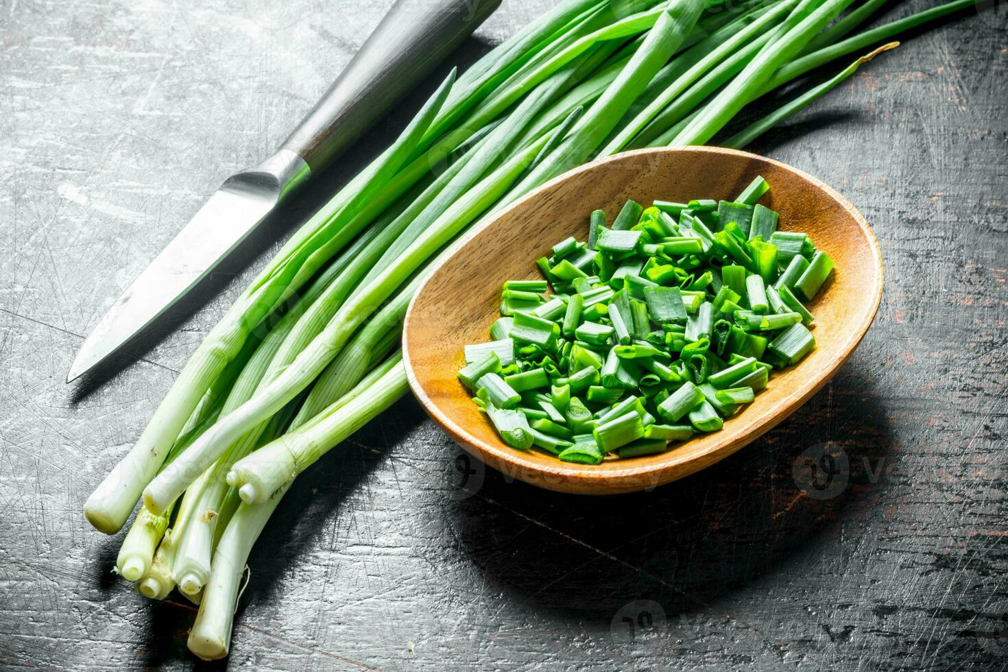 Chopped green onion in a wooden plate. photo