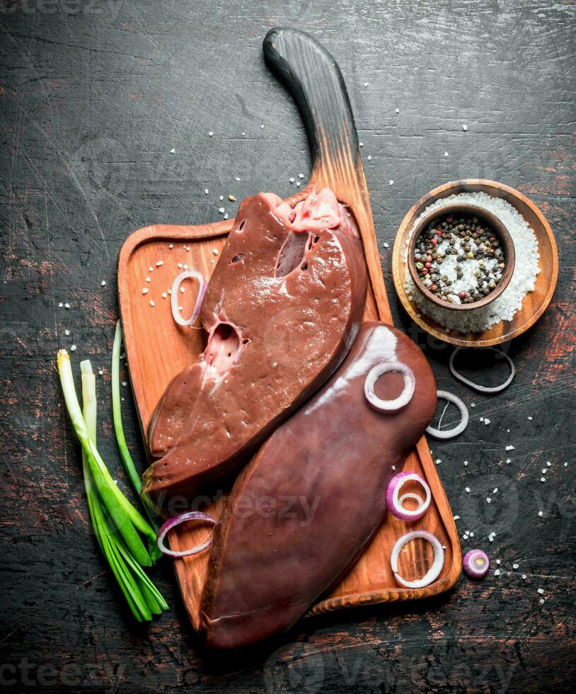 Raw liver on a cutting Board with onions and spices. photo