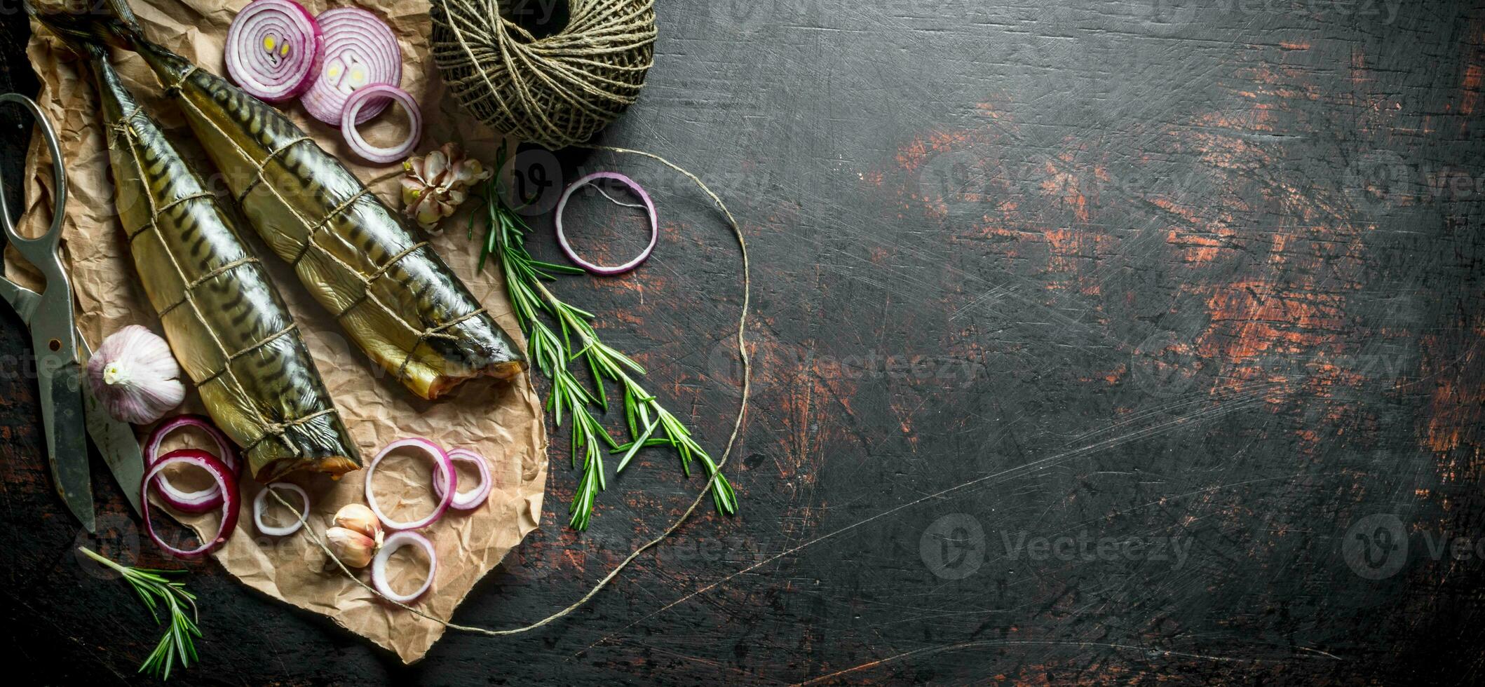 Fragrant smoked mackerel on paper with twine and chopped onion. photo