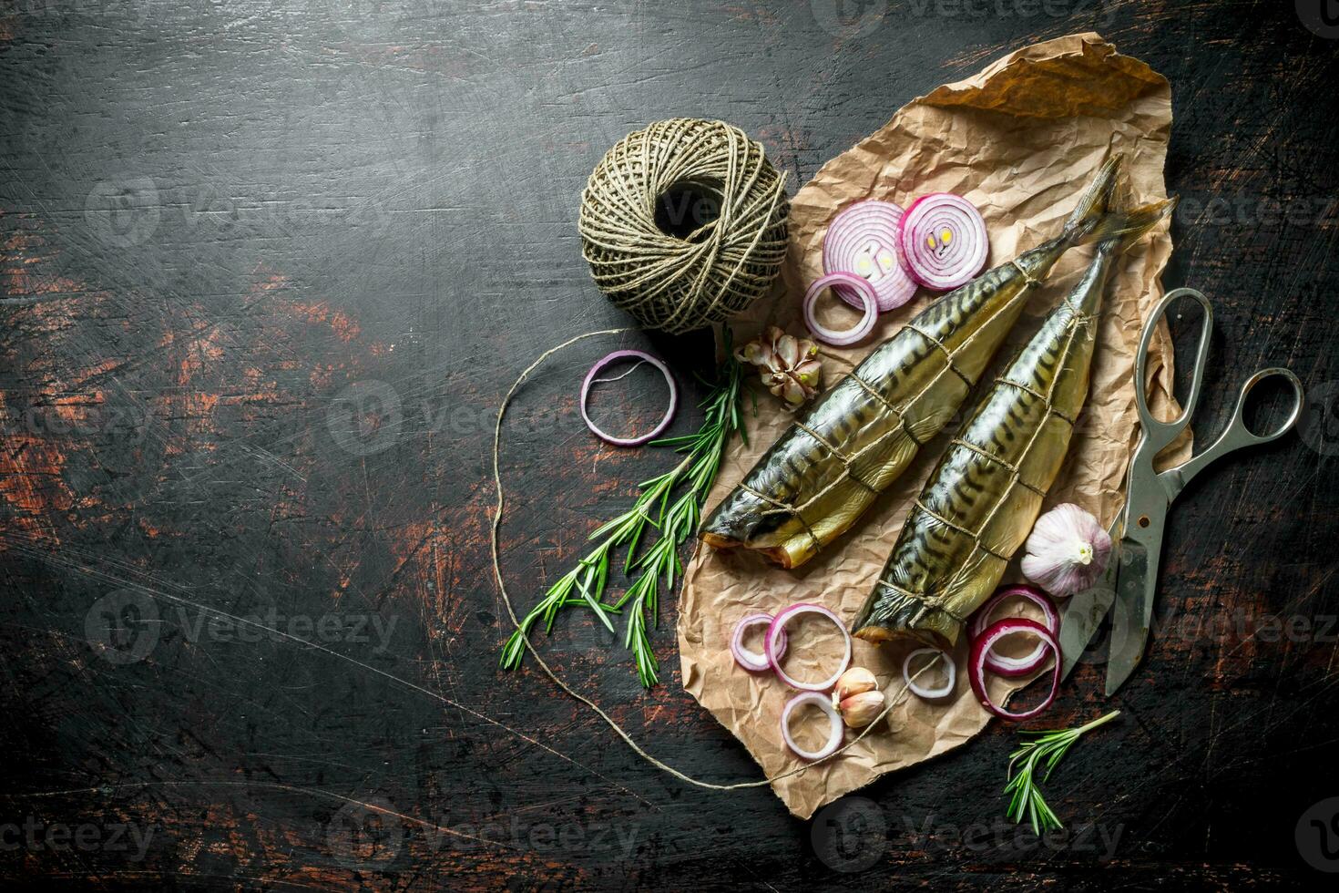 Fragrant smoked mackerel on paper with twine and chopped onion. photo