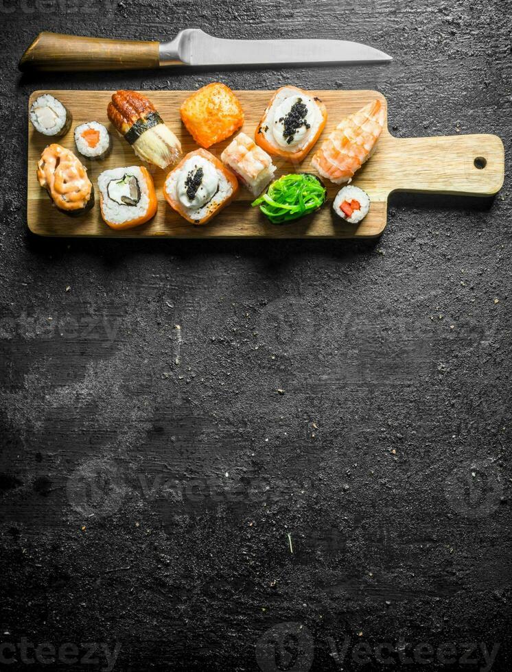 Sushi rolls with shrimp, vegetables and salmon on a cutting Board with a knife. photo