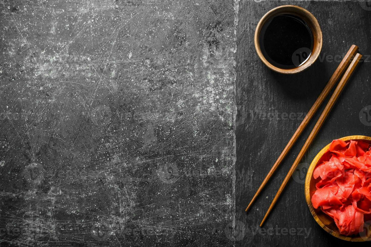 Soy sauce and marinated ginger on a stone Board with chopsticks. photo