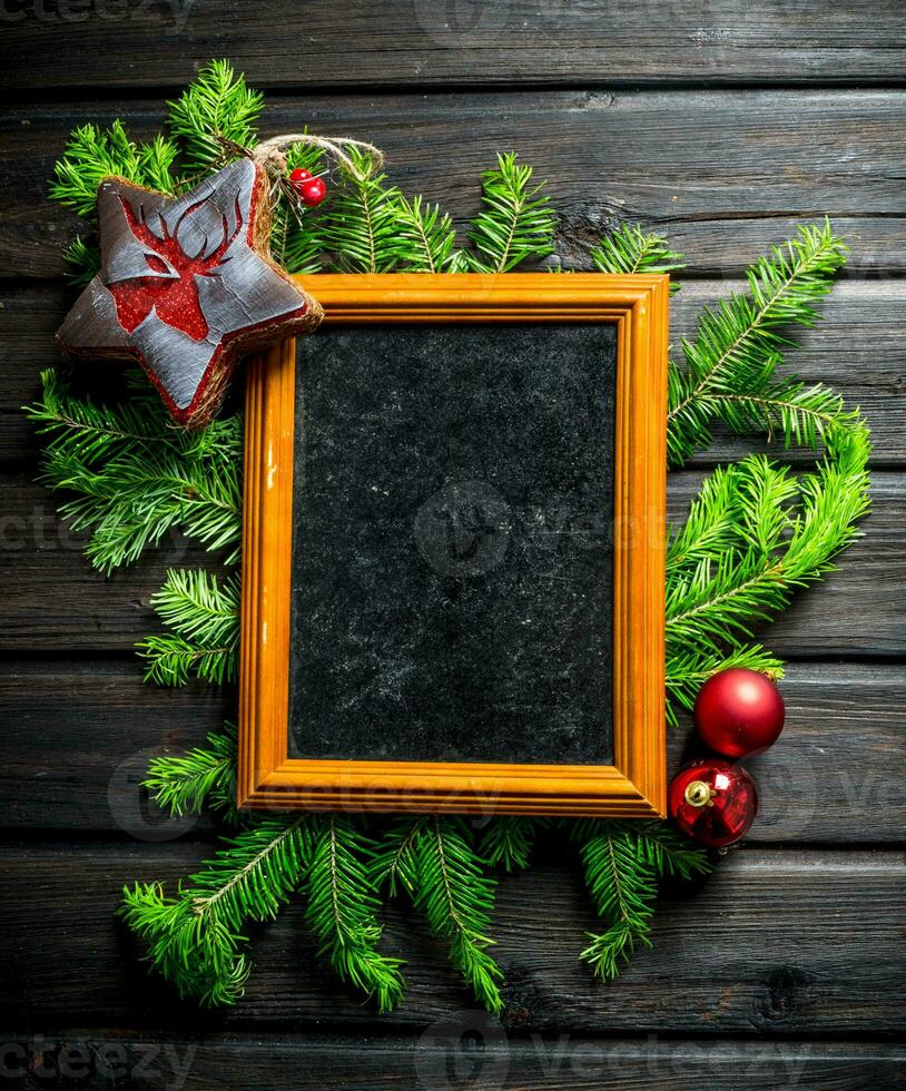 Empty Christmas photo frame with fir branches and decorations.