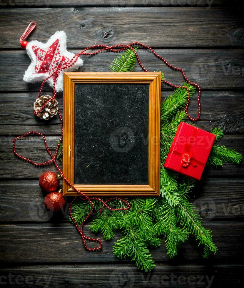 Photo frame with Christmas decorations and fir branches.