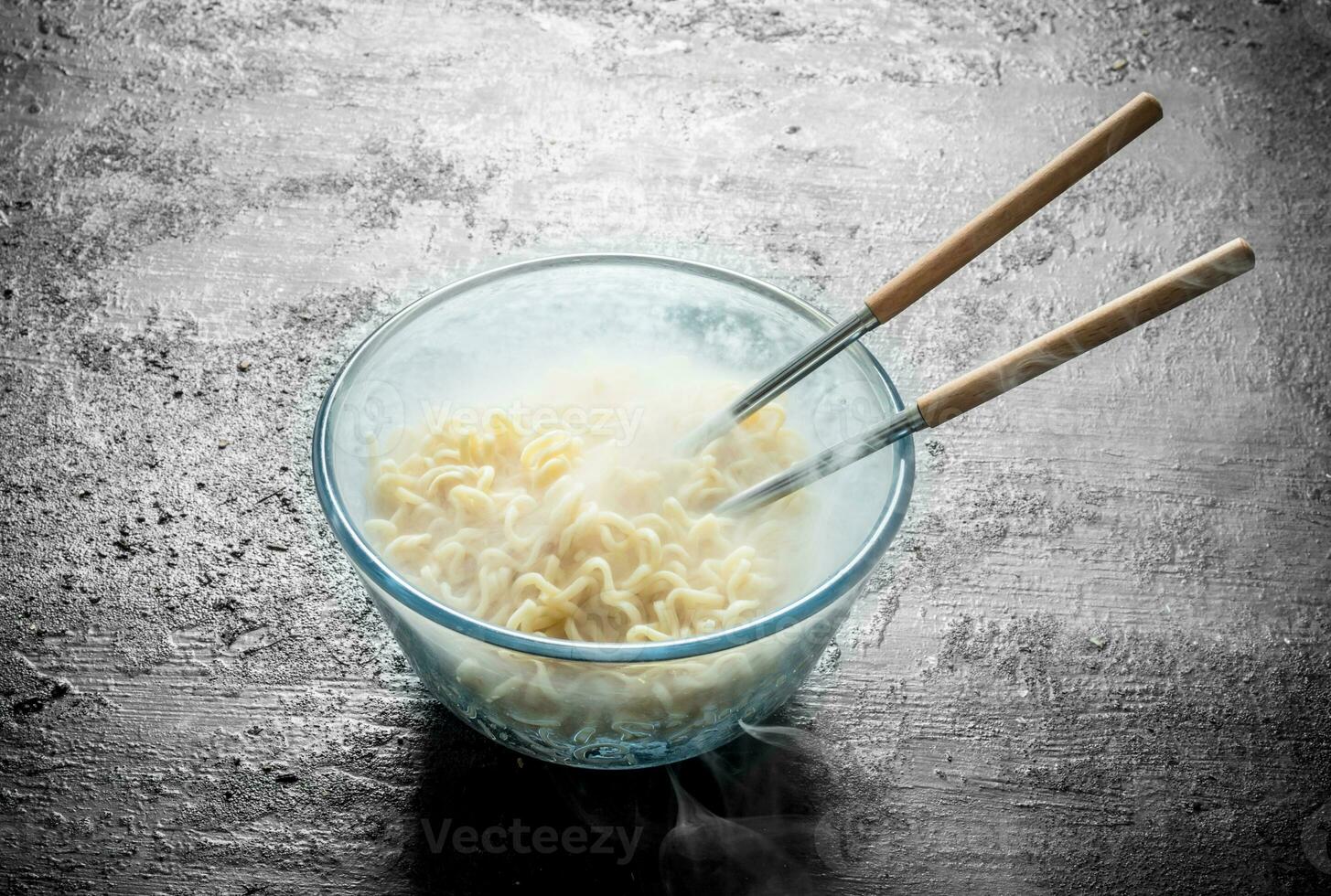 Heated instant noodles in glass bowl with chopsticks. photo
