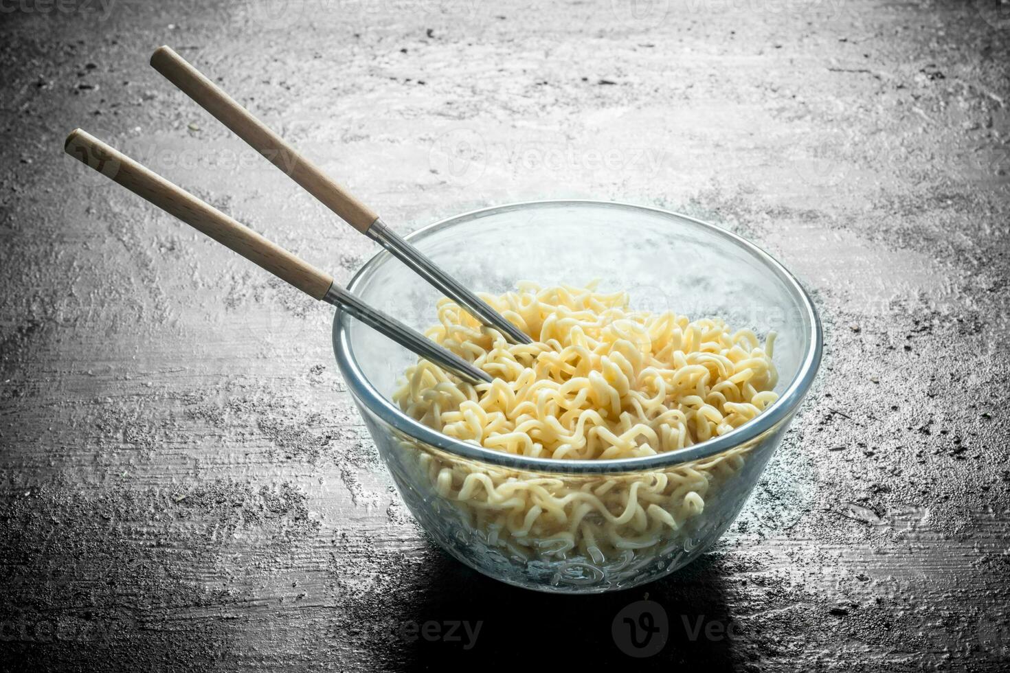 Heated instant noodles in glass bowl with chopsticks. photo