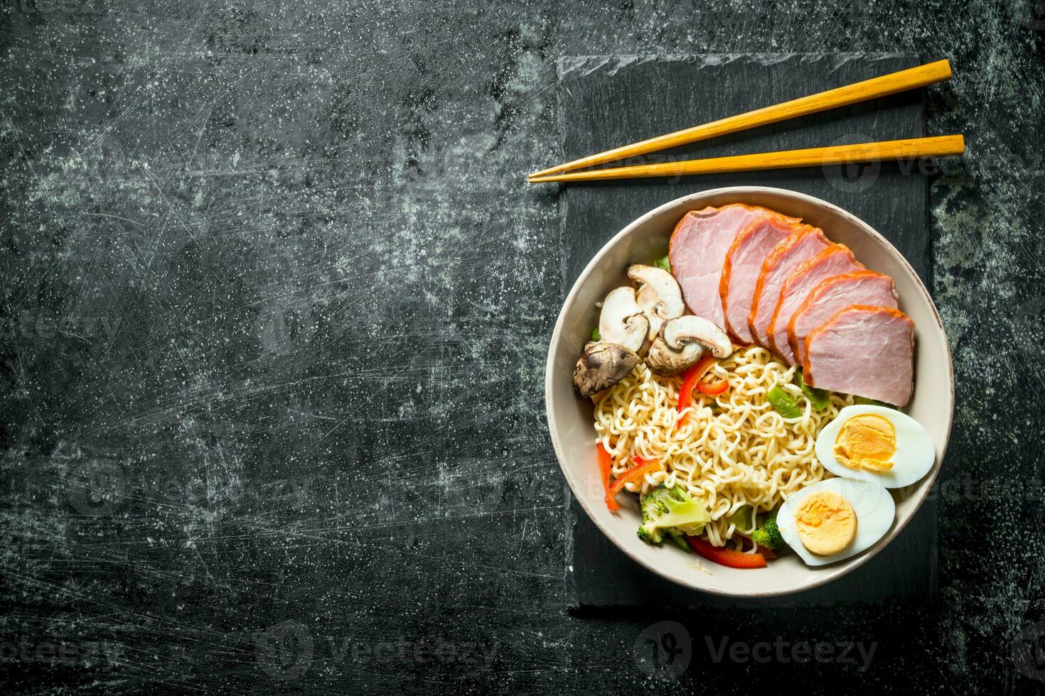 Instant noodles in bowl on stone Board with chopsticks. photo
