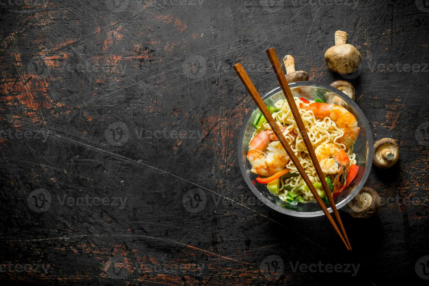 Instant noodles in a glass bowl with shrimp, vegetables and mushrooms. photo