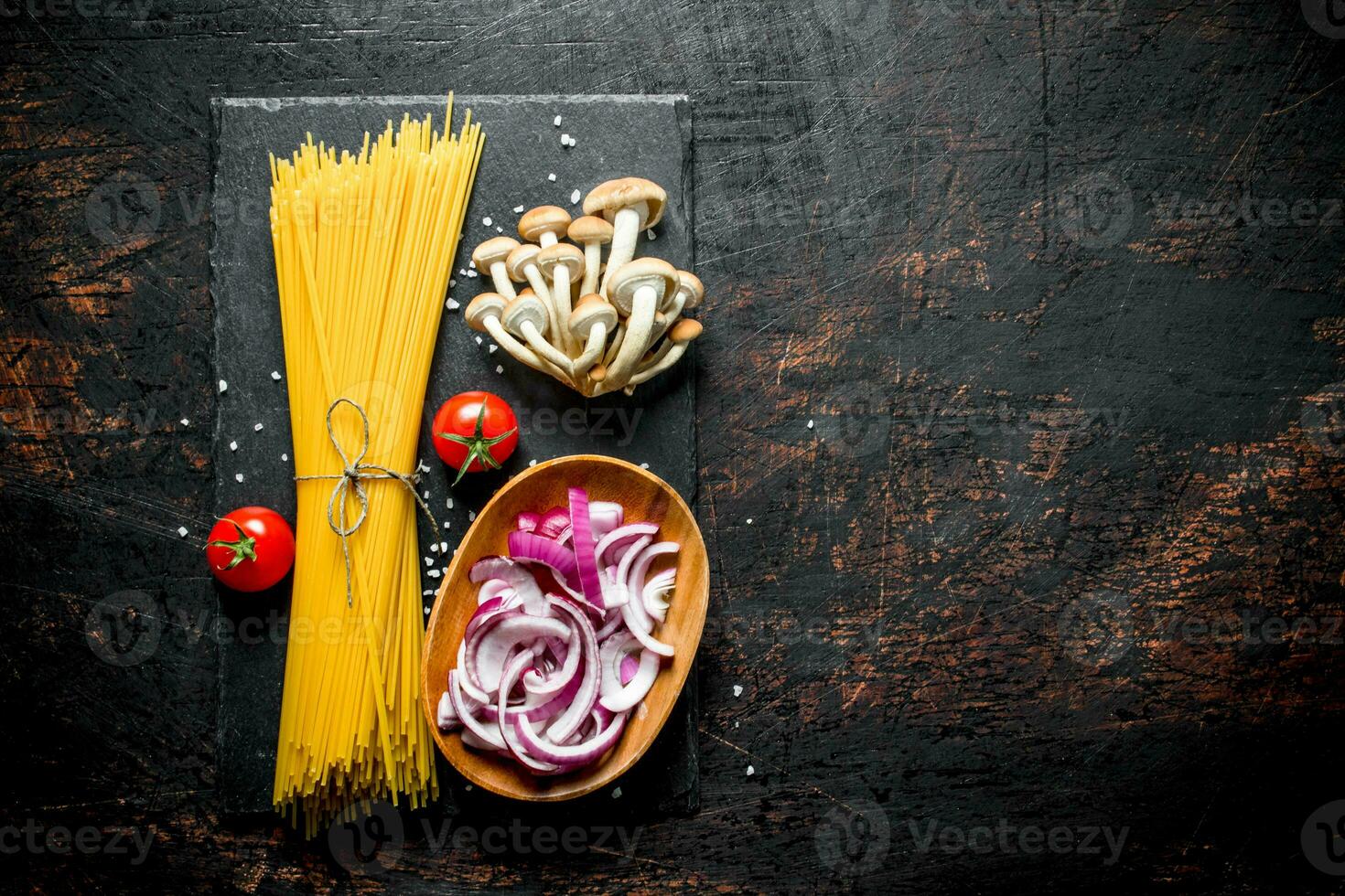 Raw spaghetti with tomatoes, mushrooms and cutting onion in bowl. photo