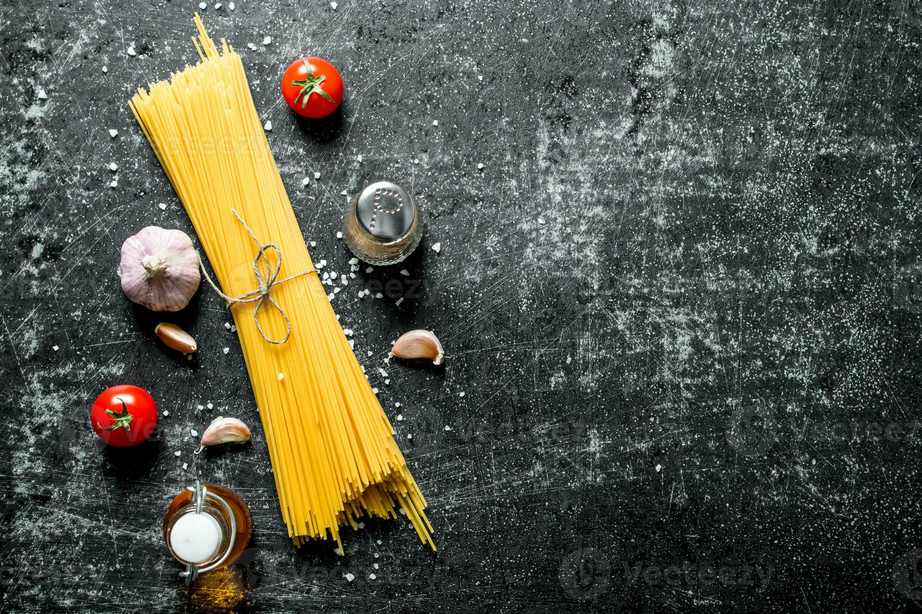 Raw spaghetti with garlic cloves and tomato. 32016899 Stock Photo at Vecteezy