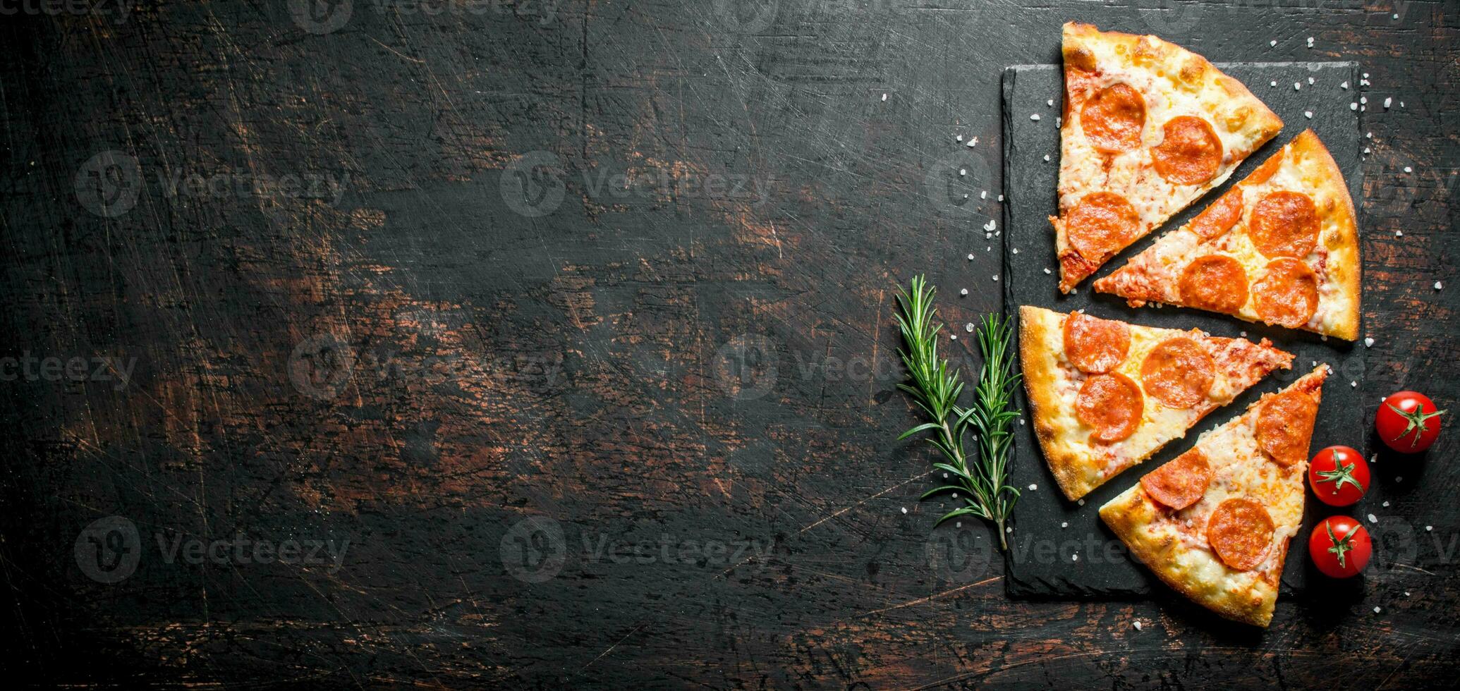Slices of pepperoni pizza with rosemary and tomatoes. photo