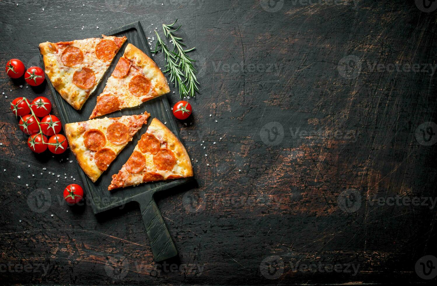 Slices of pepperoni pizza with tomatoes and rosemary. photo