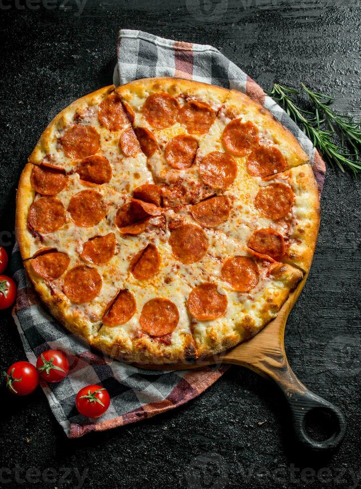 Sliced pepperoni pizza with rosemary and tomatoes. photo