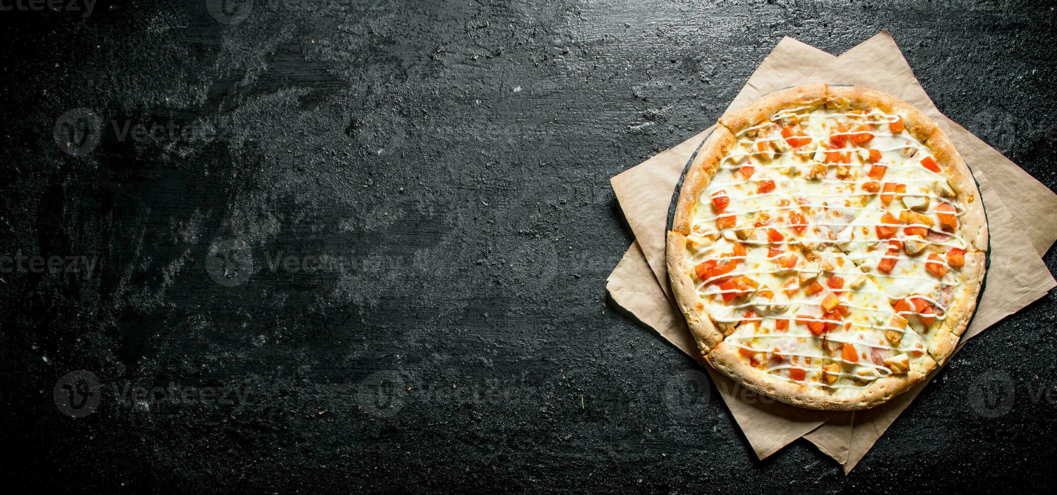 Pizza with chicken, tomatoes and cheese sauce on paper. photo