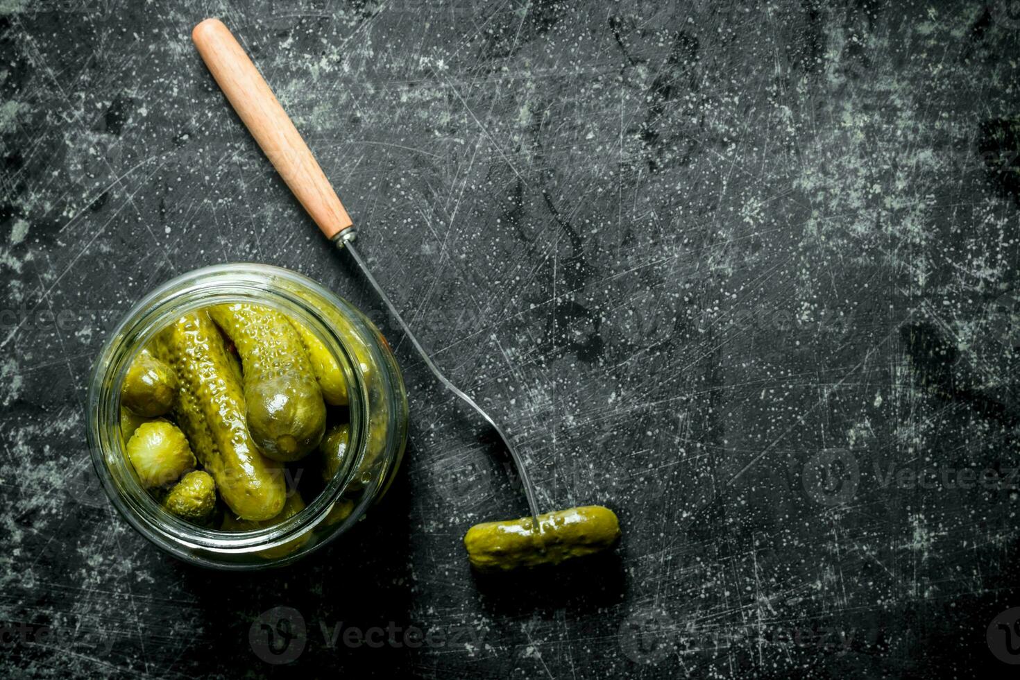 Open glass jar with pickled cucumbers. photo