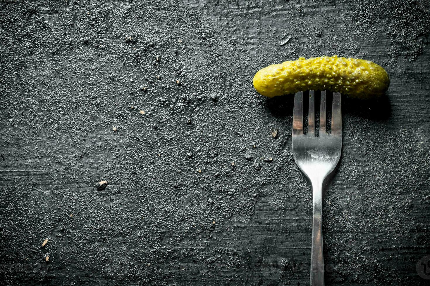 One pickled cucumber on a fork. photo