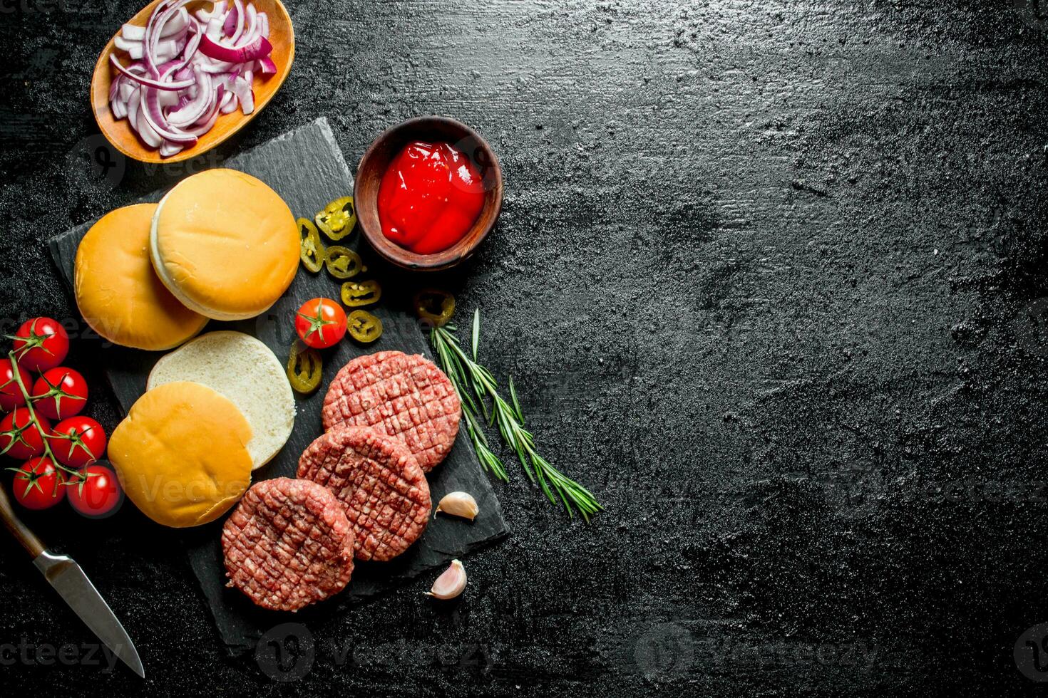 Raw burgers with tomatoes, scones, sauce and chopped onion. photo